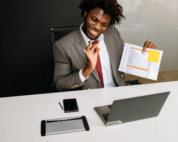 A happy man in a suit looking at his laptop.
