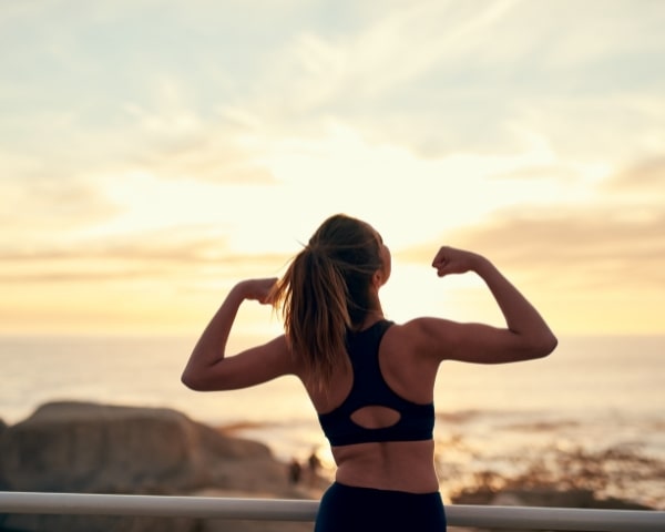 A person flexing her arms in the sun.