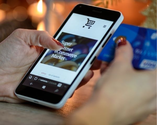 A lady using her phone ordering of a site that does ecommerce for services.