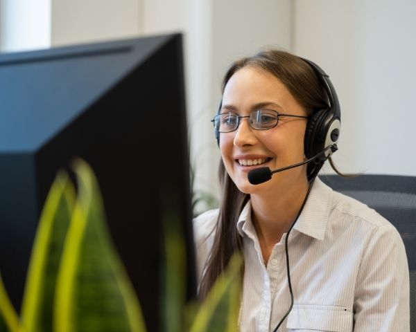 A lady from an online marketing agency working and talking to a customer on the phone through her microphone.