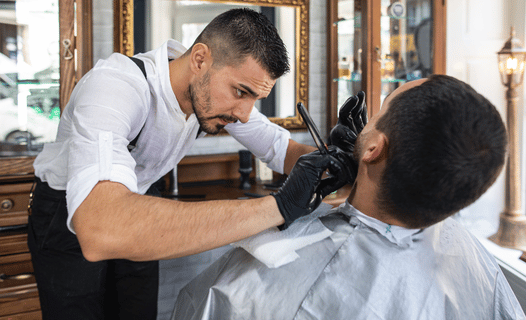 A barber working hard with a client that he received from digital marketing.