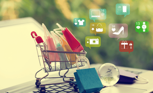 Ecommerce retailer cart holding items on top of a computer.
